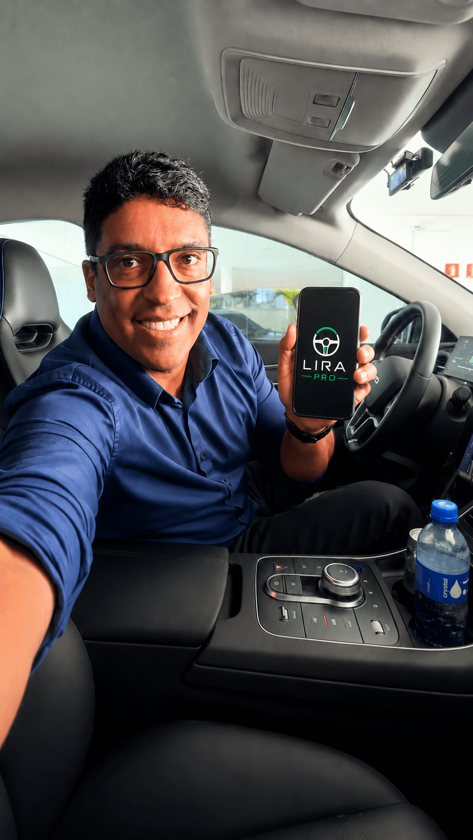 Motorista sorrindo dentro do carro, mostrando o app LIRA PRO no celular